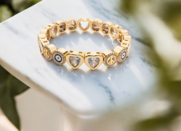 A series of three stackable macrame bracelets on an wrist, featuring gold and silver colors with bead details.